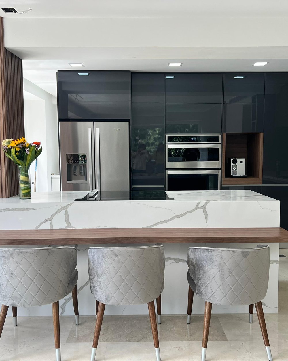 Cocina en laca negra brillante con isla de mármol y barra de madera